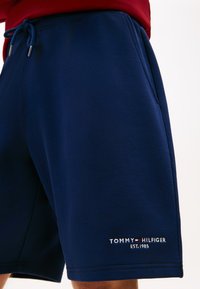 Σκούρα μπλε σορτς από απαλό ύφασμα, με ελαστική μέση και κορδόνι, καθώς και λευκό λογότυπο με τη φράση "TOMMY HILFIGER EST. 1985."