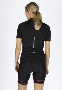 Svart cykeltröja med korta ärmar, med en bakficka och reflekterande rand. Svarta shorts med rosa detaljer och vaddering.