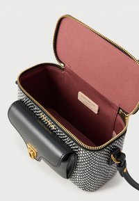 Krūšu soma ar melnu ādas pārvalku un rakstainu pinumu ārpusē. Iekšpuse ir bordo krāsā ar rāvējslēdzēja aizdari un zelta detaļām.