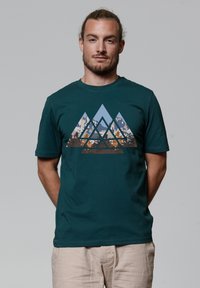 Teal katoenen t-shirt met een geometrisch bergontwerp in tinten blauw, bruin en tan, met een zachte textuur en korte mouwen.