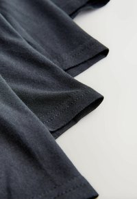 Sötétszürke pamut anyag, rövid ujjakkal, sima textúrával és tiszta varrással a szegélyeken és a széleken.