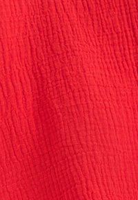 Tessuto rosso con una texture arricciata, caratterizzato da un materiale morbido e traspirante, ideale per diverse applicazioni di abbigliamento.