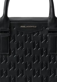Geantă din piele neagră cu un model geometric embosat, prevăzută cu două mânere superioare și o placă logo metalică Karl Lagerfeld.