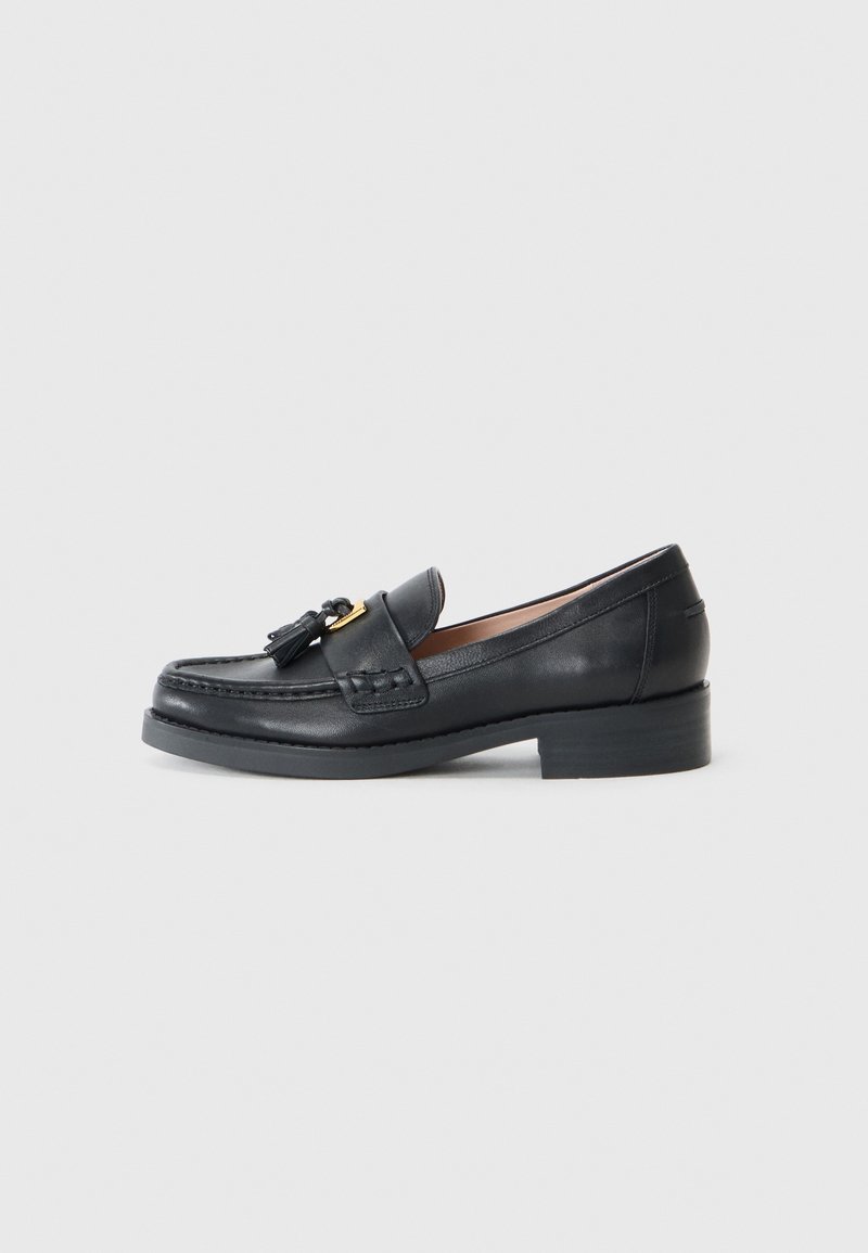 Mocassins en cuir noir avec un bout rond, des franges décoratives et un petit talon. Présente des coutures visibles et une texture lisse.