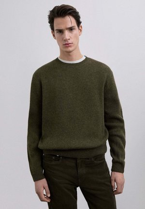 Suéter de canalé verde oliva con cuello redondo, combinado con pantalones oscuros verdes a juego. Textura suave, ajuste elástico y un diseño casual.