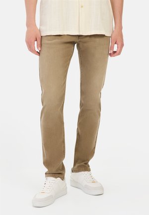 Beige straight-leg jeans with a soft texture, five pockets, and mid-rise design, paired with white sneakers.