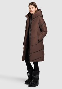 Bruine pufferjas met een hoge kraag, een ritssluiting aan de voorkant en zijzakken; bevat horizontale panelen en een grote capuchon voor extra warmte.