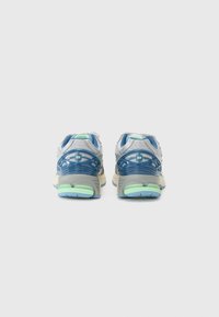 Chaussures de sport avec une tige en maille grise, des accents bleus et des détails vert menthe. Présentent une semelle rembourrée et un talon texturé pour le soutien.