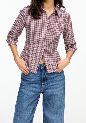 Checkered burgundy and white button-up shirt with long sleeves, casual fit, and a straight hem, paired with high-waisted blue denim jeans.