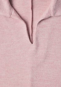 Pull en maille rose doux avec un col en forme d’encoche en V, montrant la texture détaillée et les coutures sur le tissu.