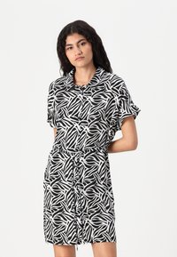Φόρεμα κοντομάνικο σε μαύρο και λευκό, με κυματιστό αφηρημένο μοτίβο, μπροστά με κουμπιά και με κορδόνι στη μέση για ρυθμιζόμενη εφαρμογή.