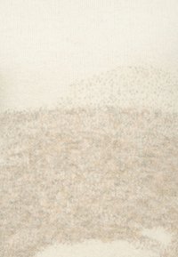 Bež i krem pleteni materijal s mekanom teksturom, s gradijentnim uzorkom koji prelazi iz čvrste kreme u umirujući bež.