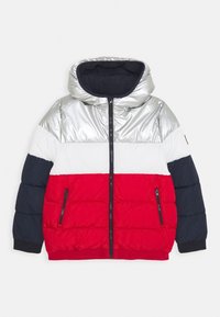 Puffjacka med en färgglad design i silver, vitt, rött och marinblått. Har huva, framzipper och sidofickor med dragkedja. Kviltat mönster.