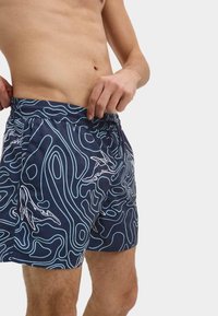 Zwemshorts in donker marineblauw met een golvend patroon in wit. Elastische tailleband met een trekkoord. Boven de knie lengte, lichtgewicht stof.