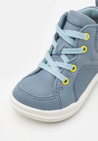Blauer Leder-Hochtop-Sneaker mit hellblauen Schnürsenkeln, gelben Ösen, weißer Gummisohle und kontrastierenden Nähten entlang der Kanten.