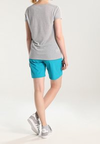 Šedé tričko s krátkým rukávem doplněné tyrkysovými šortkami. Šortky mají hladkou strukturu a uvolněný střih, k tomu se hodí šedé tenisky.