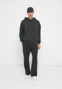 Dunkelgrauer Hoodie und passende Jogginghose, aus einem weichen Stoff gefertigt. Weiße Turnschuhe runden das Outfit ab. Einfaches Design mit lässigem Schnitt.