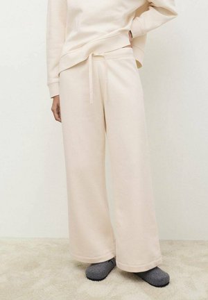 Pantalones de chándal beige con cintura elástica y cordón. Los pantalones son de pierna ancha, fabricados con material suave, sin patrones ni acentos visibles.