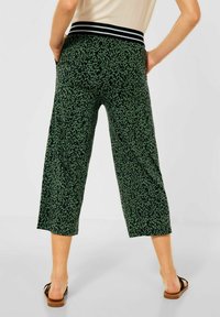 Gröna shortsbyxor med ett svart djurmönster, elastisk midjeband med vita ränder och fickor på sidorna.