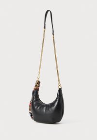 Sac en cuir noir à bandoulière avec une forme arrondie, doté d'une anse en chaîne dorée et d'un accent en tissu à motif coloré sur un côté.