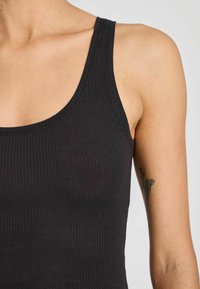Must have mustriga tank top, mille avarate rihmad ja ümardatud kaelus, valmistatud venivast kangast, millel on sile tekstuur ja liibuv siluett.
