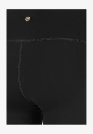 Leggings noirs en tissu extensible, dotés d'un design sans couture, de coutures à plat et d'un petit logo doré près de la taille.