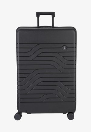 Valigia rigida nera con una superficie testurizzata a onde, manico retrattile e quattro ruote per la mobilità. Presenta un logo circolare sul davanti.