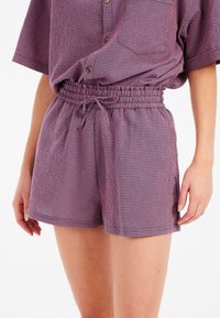 Pantaloni corti a scacchi viola e rosa con vita elastica, dettaglio con cordino e tasche laterali, realizzati in tessuto leggero.