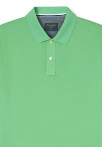 Groene polo in een textuur gebreid, voorzien van een twee-knopen sluiting, korte mouwen en een contrasterende kraagafwerking. Maat M.