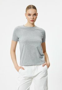 Heather grå T-shirt med korte ærmer, rund halsudskæring og lysegrøn broderet tekst "vær ikke alene" på forsiden.