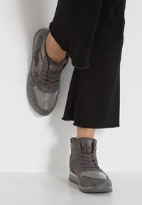 Šedé vysoké tenisky vyrobené z semiše a síťoviny, s blyštivými akcenty, texturovanými panely a šněrováním vpředu s bočním zipem.