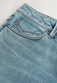 Lyseblå denimjeans med en falmet finish, der har en lomme foran, bæltestropper og kontrasterende syning langs sømmene.