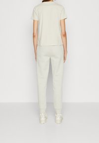 Maglietta in cotone grigia chiara e pantaloni da tuta abbinati. L'outfit presenta una vestibilità comoda con una texture liscia e dettagli di cucitura sottili.