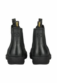 Botas de cuero negras hasta el tobillo con una suela de goma texturada, pestañas en la parte posterior y un detalle de costura mínima en la parte superior.
