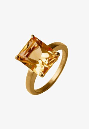Anillo de oro con una gran gema amarilla de corte cuadrado sostenida por cuatro garras en una banda circular lisa sobre un fondo blanco.