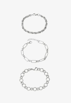 Trzy srebrne bransoletki: górna z plecionym wzorem ogniw, środkowa z wydłużonymi ogniwami w kształcie spinacza biurowego, dolna z skręconymi owalnymi ogniwami z zapięciem.