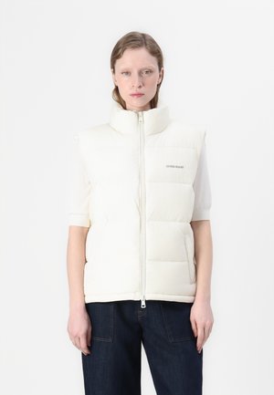 Witte gewatteerde vest met hoge kraag, ritssluiting aan de voorkant en logo aan de linkerkant. Beschikt over korte mouwen en een gladde, glanzende textuur.
