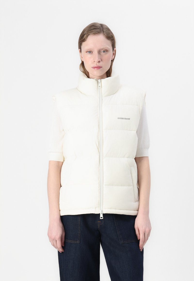 Witte gewatteerde vest met hoge kraag, ritssluiting aan de voorkant en logo aan de linkerkant. Beschikt over korte mouwen en een gladde, glanzende textuur.