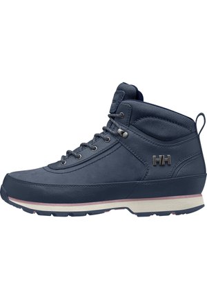 Bota de senderismo alta azul marino con cordones en la parte frontal, cuello acolchado en el tobillo, suela blanca y rosa, y logotipo metálico "HH" en el lateral.