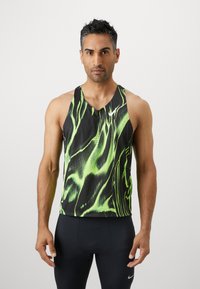 Canottiera atletica nera con motivo ondulato verde, dotata di scollo a V, design senza maniche e logo Nike sul petto. Tessuto morbido.