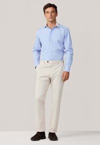 Lichtblauw button-up shirt met een witte kraag, gecombineerd met crèmekleurige chinos en donkerbruine schoenen. Heeft een borstzak en een gladde textuur.