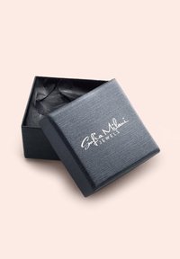 Schwarze, strukturierte Schmuckschatulle mit passendem Deckel, auf dem in weißer Schrift "Sofia Milani Jewels" gedruckt ist. Im Inneren befindet sich schwarzes Seidenpapier.