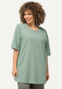 T-shirt verde chiaro a maniche corte realizzato in tessuto morbido e liscio. Presenta una scollatura rotonda e una vestibilità rilassata e oversize.