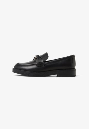 Black leather loafer with a round toe, decorative stitching, a small bow detail on the vamp, and a low, textured black sole.