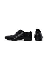 Schwarze Leder-Dressschuhe mit glatter Oberflächenstruktur, Wingtip-Design, runder Zehenpartie und niedrigem Absatz. Mit dekorativen Nähten entlang der Kanten.