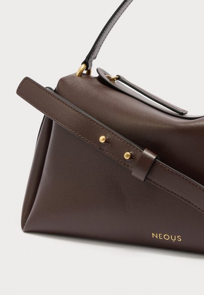 Τσάντα από σκούρο καφέ δέρμα με ρυθμιζόμενο λουρί ασφαλισμένο με δύο χρυσά καρφιά, με επάνω λαβή και χρυσό λογότυπο «NEOUS» στη γωνία κάτω δεξιά.