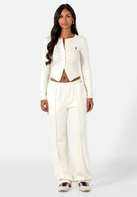 Korte mouwen cropped cardigan en wijde broek set, beide in off-white stof, met knoopsluitingen en subtiele logo-accenten.