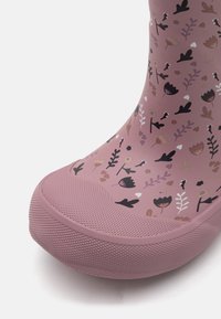 Botte de pluie en caoutchouc rose avec un motif floral agrémenté d'accents noirs et beiges, semelle texturée et design à bout arrondi.