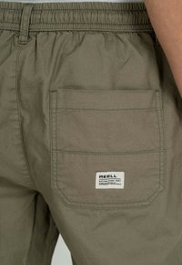 Cargohosen aus olivgrünem Baumwollstoff mit elastischem Bund, einer einzelnen Gesäßtasche und einem angenähten Markenlabel.