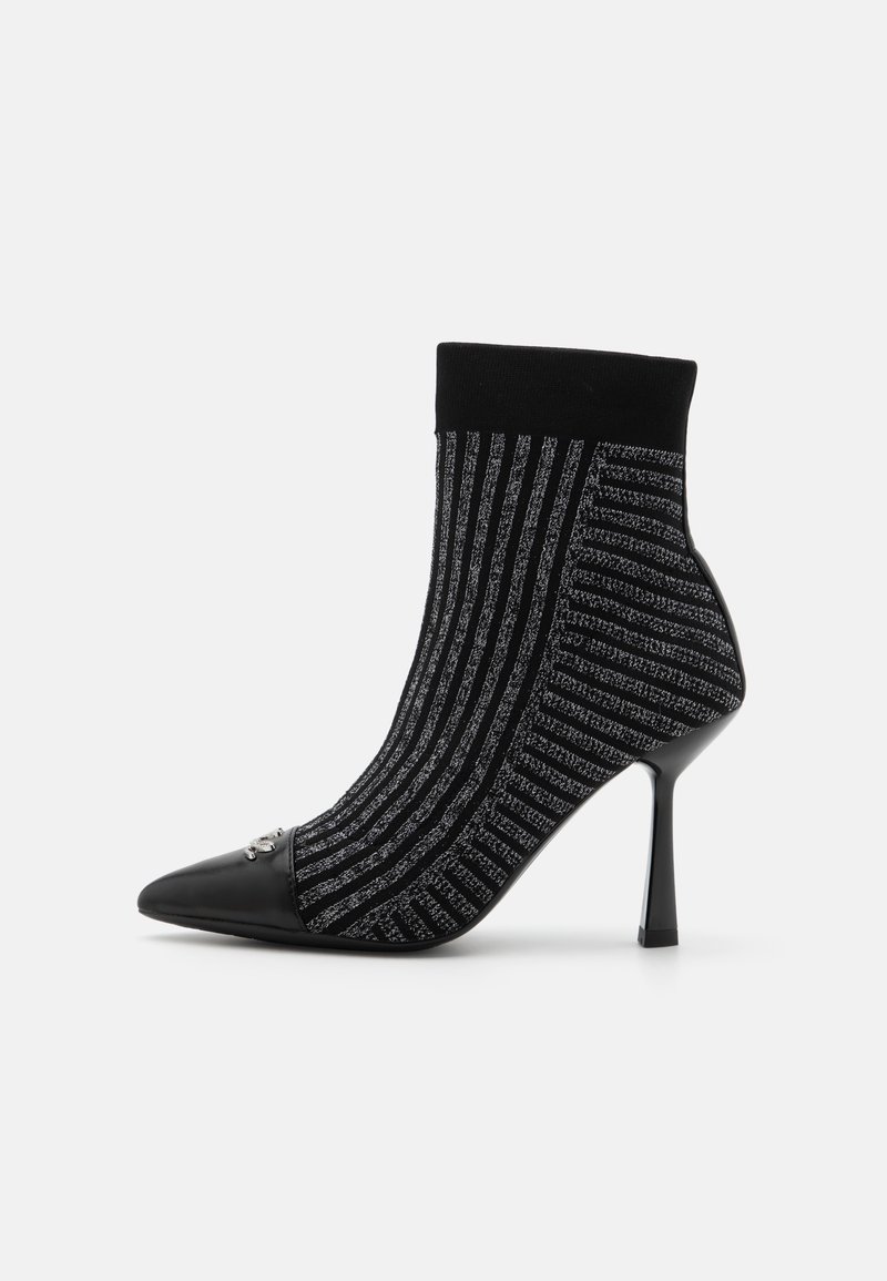 Bottine en tricot avec un motif rayé noir et argent, bout pointu et talon aiguille haut. Présente un revers noir uni en haut.